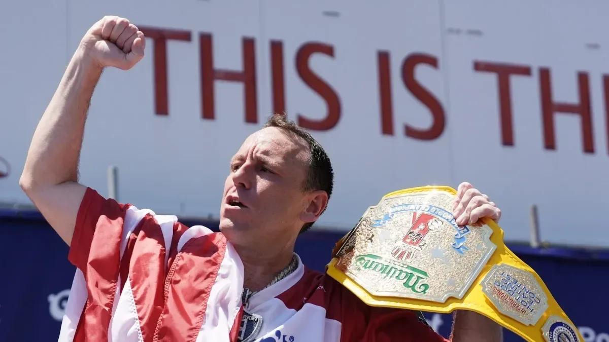 Joey Chestnut devorando varios hot dogs en un concurso de comida al aire libre