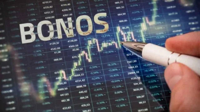 Mano sosteniendo billetes de dólar y bonos financieros sobre fondo de gráficos bursátiles