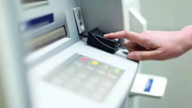 Mano sosteniendo un cheque bancario junto a un formulario de impuestos y una calculadora
