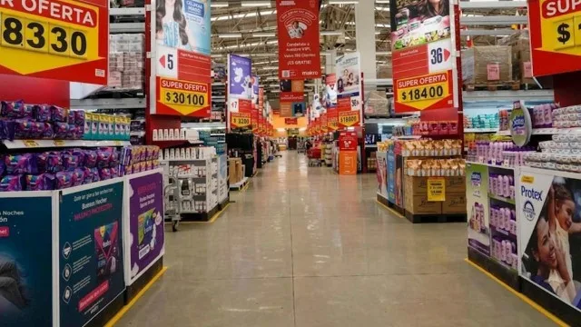 Empleados de supermercado en una góndola con expresión de preocupación mientras un supervisor habla con ellos