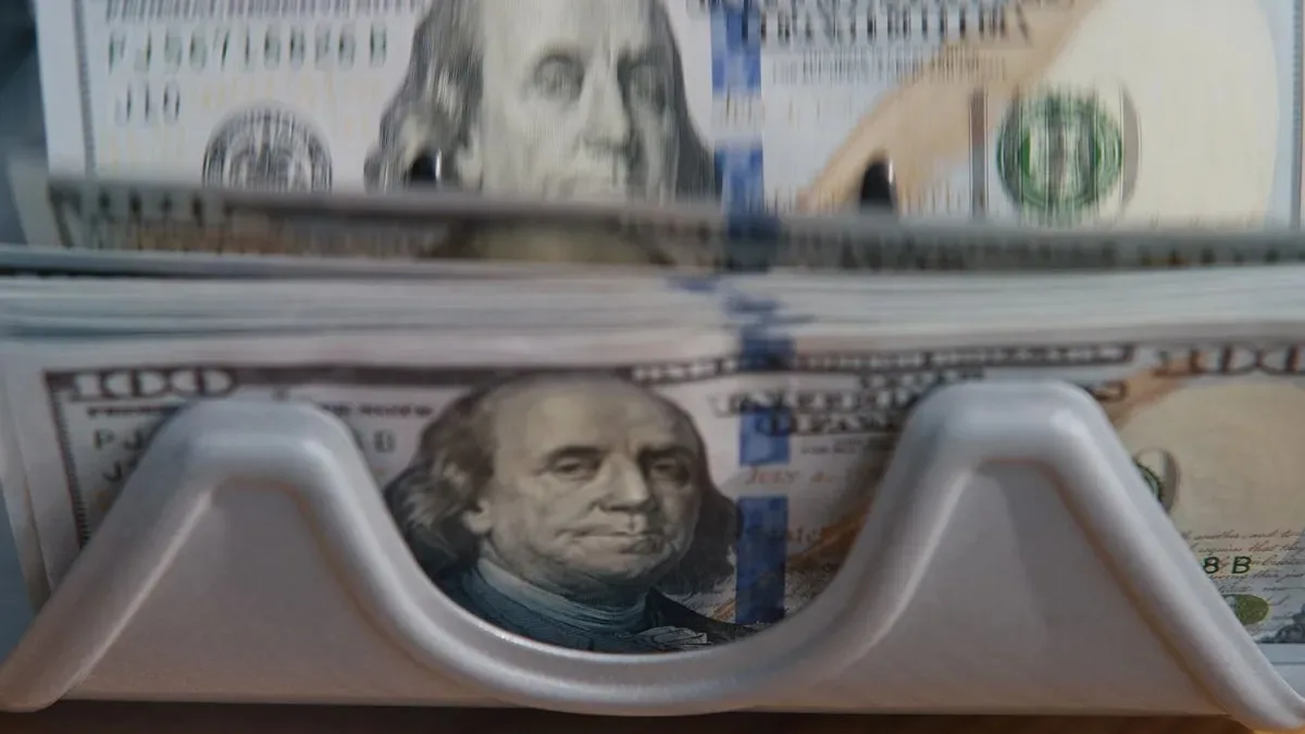 Billetes de dólares estadounidenses apilados sobre un fondo de gráficos financieros