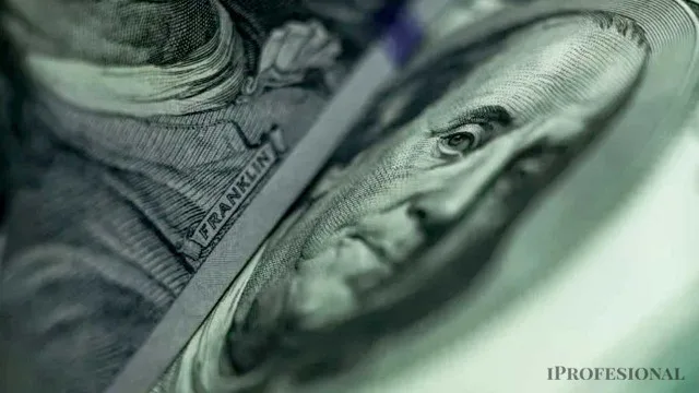 Billetes de dólares estadounidenses apilados sobre una mesa junto a una alcancía y una libreta bancaria
