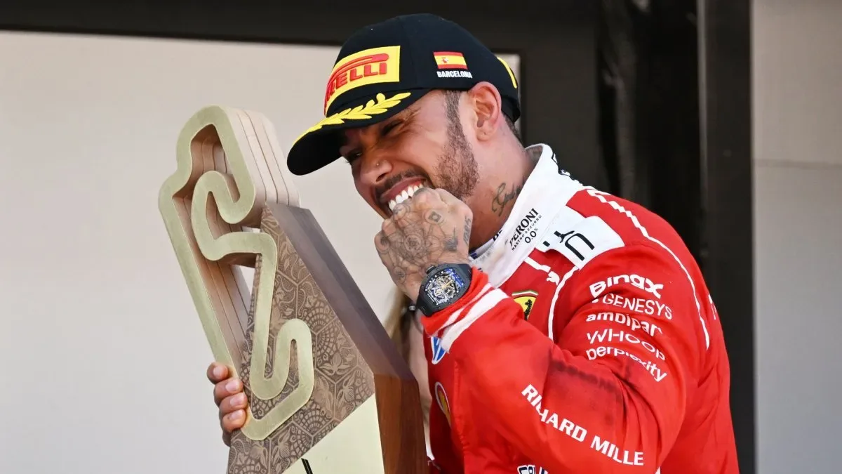 Lewis Hamilton sonriente con trofeo de campeón de Fórmula 1 y casco en mano