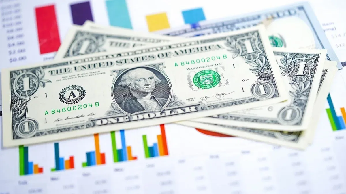 Billetes de dólares y pesos argentinos sobre un gráfico de cotizaciones