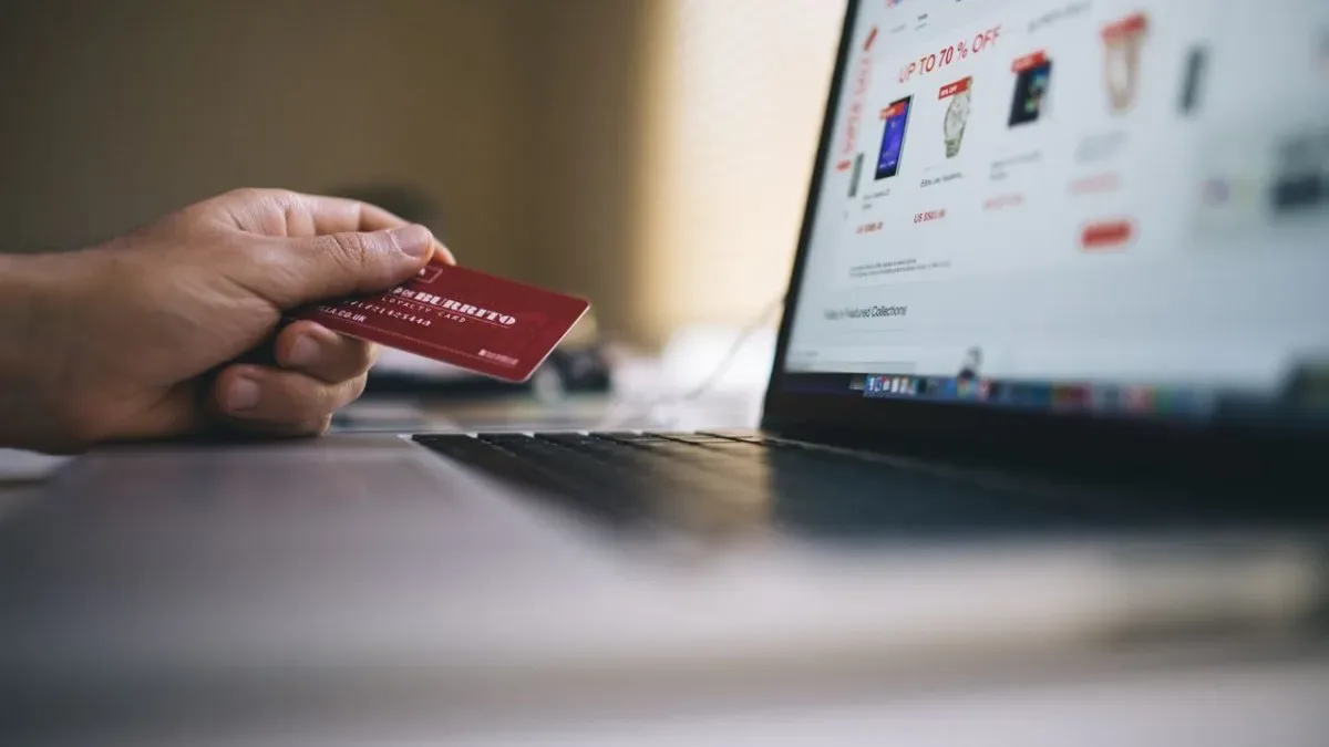 Persona joven revisando celular con notificaciones de ventas y comisiones en plataformas digitales