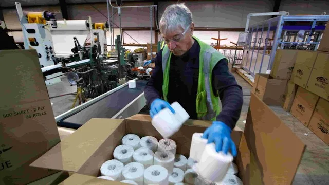 Empleado de Lustramax sosteniendo rollos de papel higiénico en una fábrica