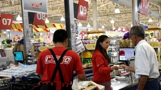 Empleados de supermercado Coto trabajando en caja registradora