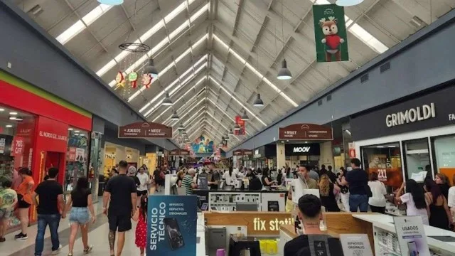 Interior de un shopping outlet en Buenos Aires con carteles de descuentos en marcas como Adidas y Grimoldi