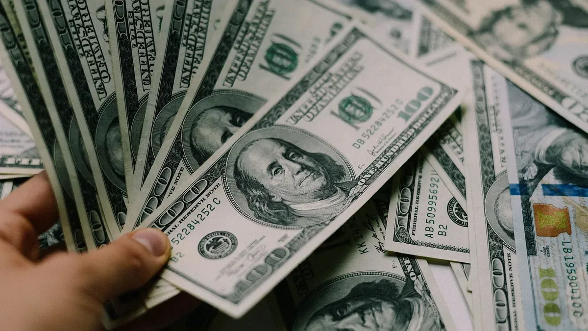 Billetes de dólares azules apilados con cotización en pantalla digital