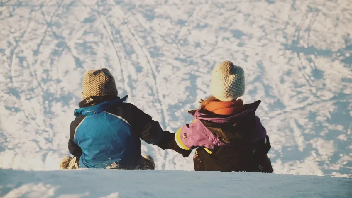 Turistas caminando por una calle nevada en Bariloche con montañas al fondo