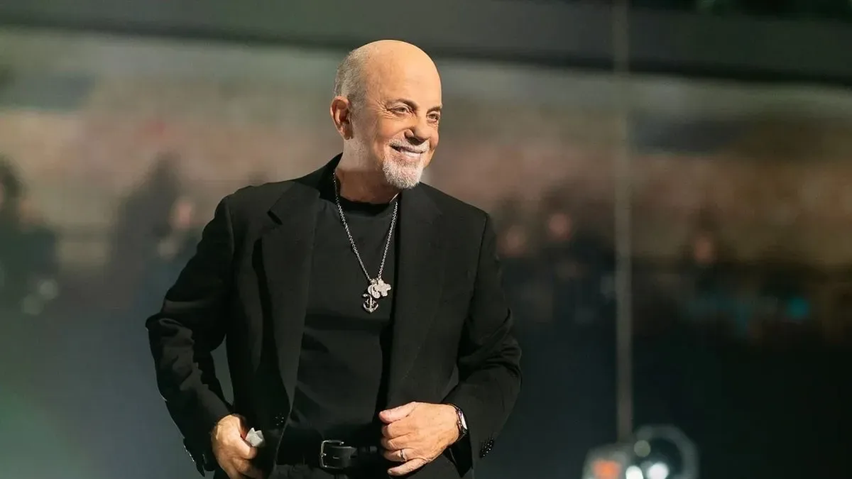 Billy Joel en concierto con micrófono y piano de fondo