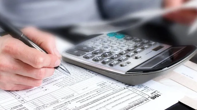 Escritorio con calculadora, formularios impositivos y laptop en oficina argentina