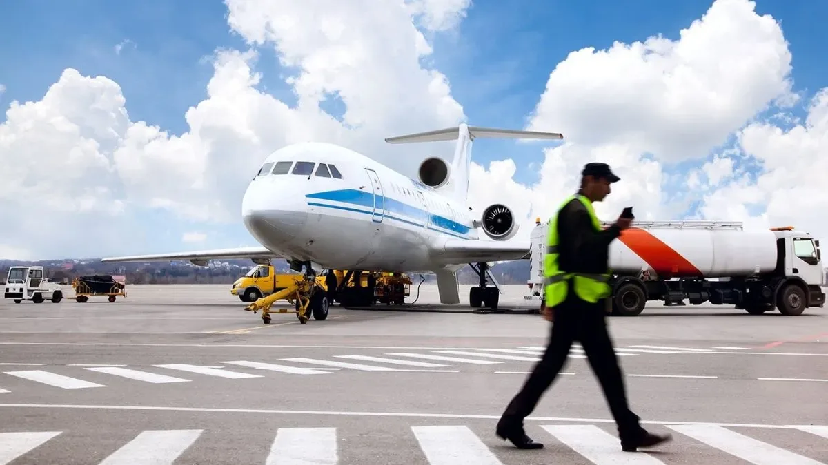 Avión comercial en pista de aeropuerto con personal de rampa trabajando en la carga