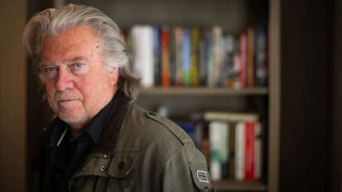 Steve Bannon en traje oscuro con expresión seria, fondo de pantalla de televisión antigua