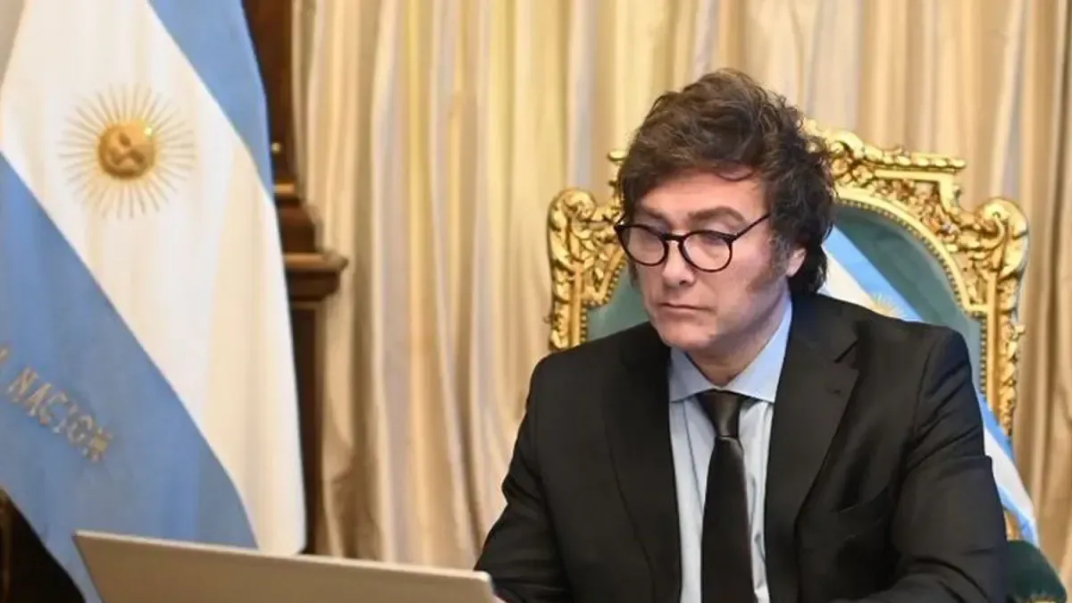 Javier Milei y Demian Reidel en un evento formal, con gráficos económicos al fondo