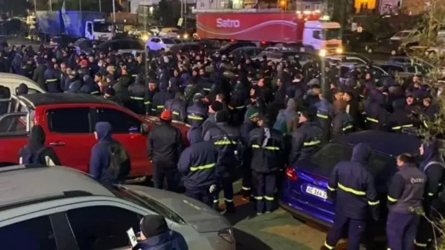 Trabajadores de logística cervecera en planta de distribución con camiones de Quilmes