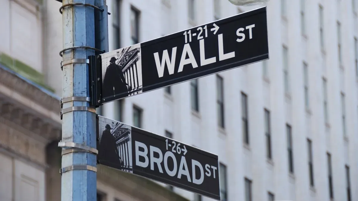Gráfico de Wall Street con flecha descendente y logo de Goldman Sachs en el fondo