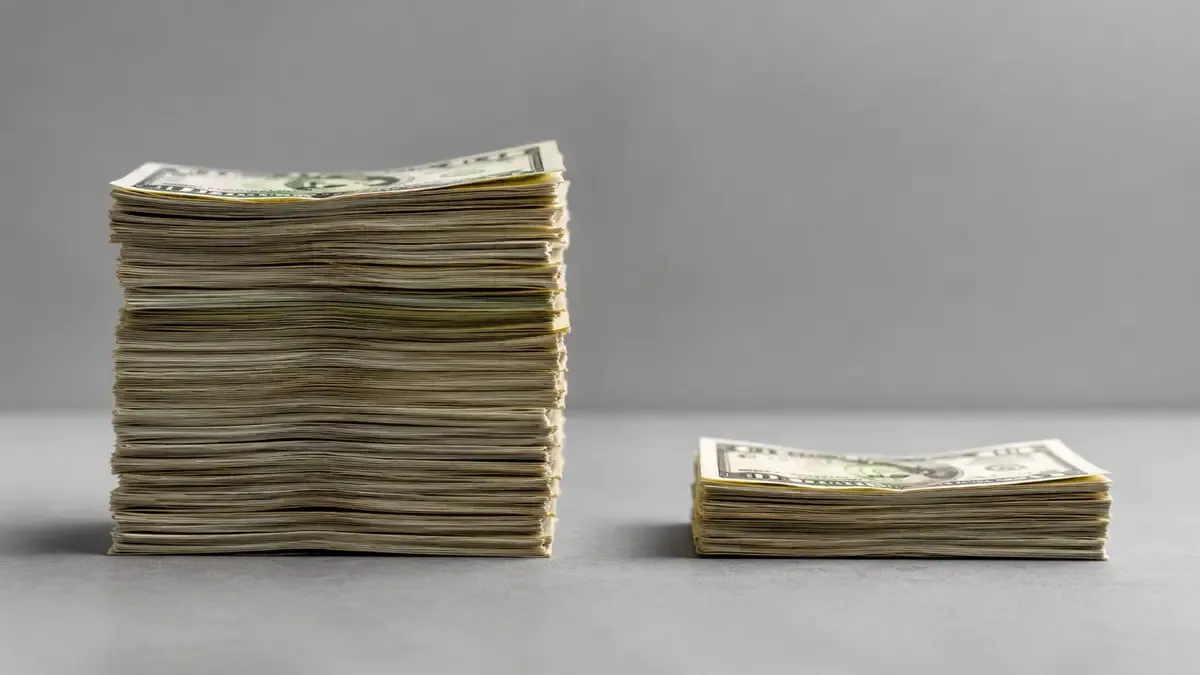 Dos pilas de billetes de distinta altura enfrentadas sobre una mesa